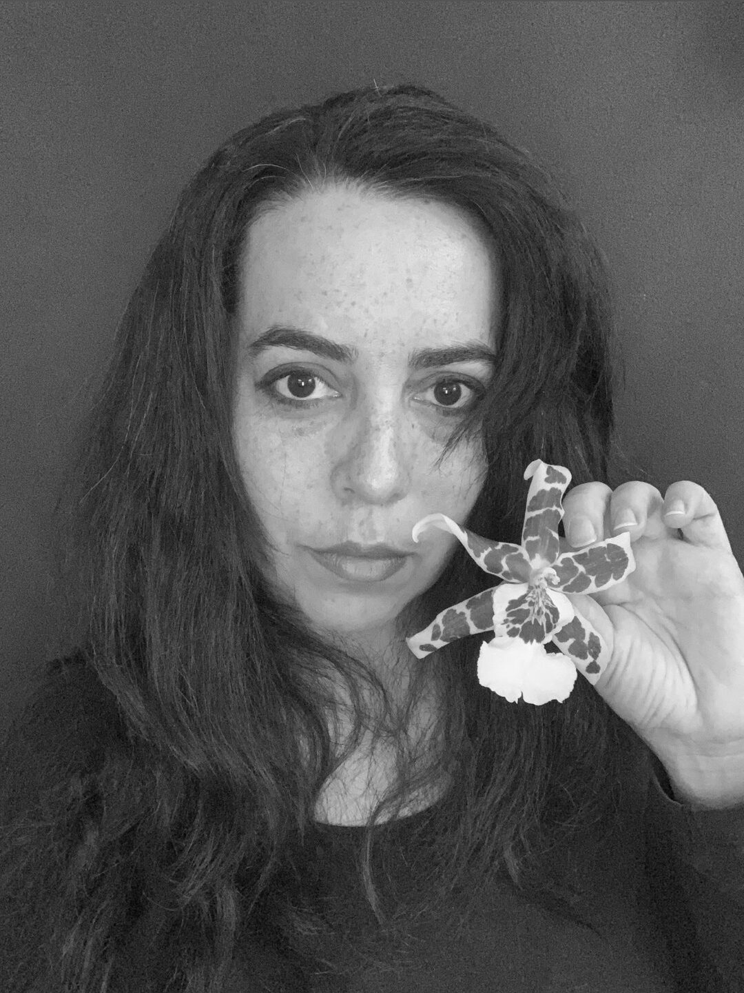 black and white picture of the artist Victoria Beyer holding an orchid